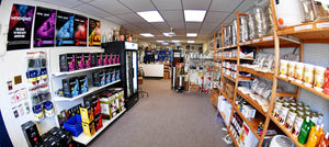 Inside Brew Your Own Beer in Havertown, PA. A long room with grey carpet and fluorescent lights. Shelves of beer equipment and supplies are along each wall.